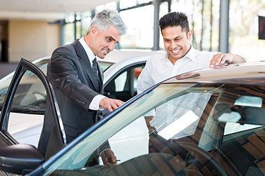 A man with a car salesmen looking at a new car. A man with a car salesmen looking at a new car.