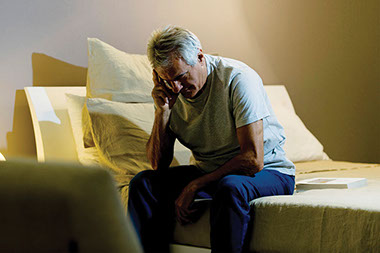 Image of older man sitting up in bed.