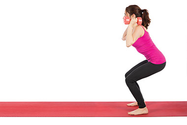 Image of women doing squats while holding dumb bells.