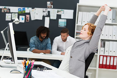 Women sitting at desk, stretching arms above her head.