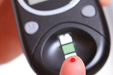 Image of pricked finger about to test blood glucose levels.