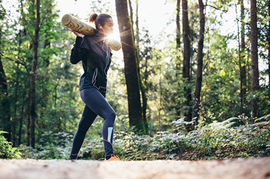 Woman working out in forrest lifting weights.
