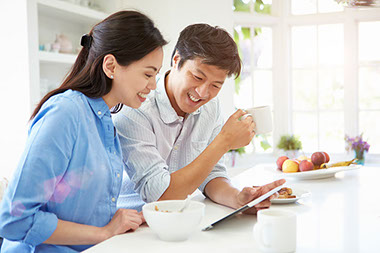 Image of couple smiling over breakfast.