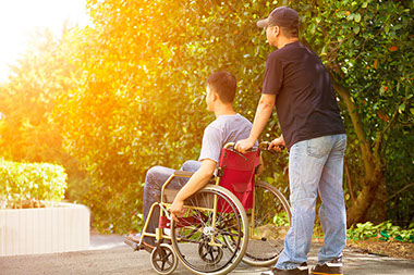 Stress relief for caregivers Image of a caregiver helping a man in a wheelchair.