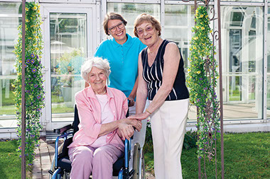 Image of elderly female in wheechair with two caregivers.