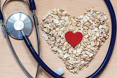 Simple ways to lower cholesterol. Image of oats shaped in a heart.