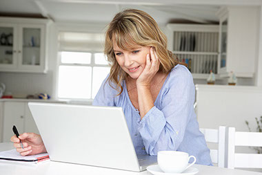 Image of women writing and on her laptop.