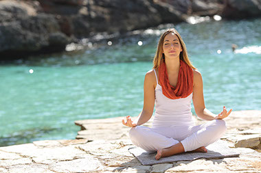 Image of women mediating outside by water.