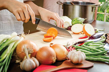 Sensational six-layer dinner. Image of a person cutting carrots.