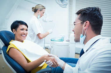 Image of women sitting in dental chair shaking hands with the dentist.