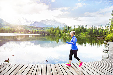 Image of older women walking on bridge along a lake.