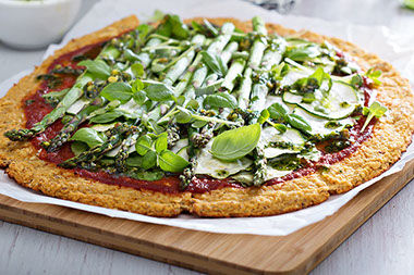 Cauliflower pizza with spinach, zucchini and asparagus.