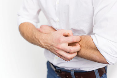 Image of man itching arm.