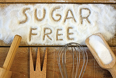 Easy ways to cut back on sugar. Image of sugar spilled out on a table with the words "Sugar Free" spelled out.