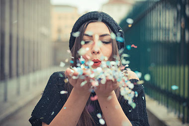Women blowing a handful of paper confetti. Women blowing a handful of paper confetti.