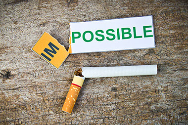 Broken cigarette with a paper ripped to spell Possible from Impossible.