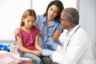 Image of mother comforting young daughter as she gets a shot.
