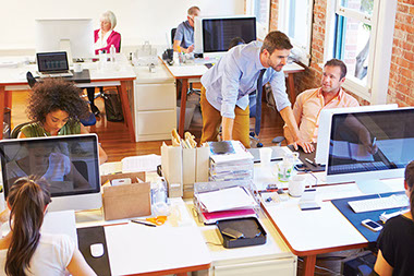Image of office with employees working on computers.