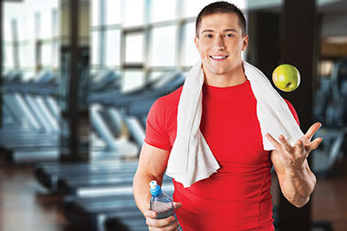 Man at gym holding a water bottle and apple.