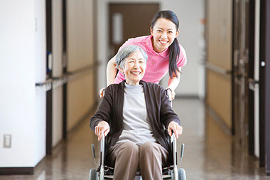 Image of older women in wheelchair being helped by relative.