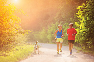 Beating exercise barriers. Image of older couple jogging with their dog.