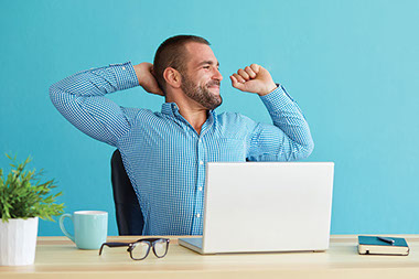 Man stretching at desk.