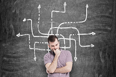 Man thinking in front of black chalk board with arrows pointing. Man thinking in front of black chalk board with arrows pointing.