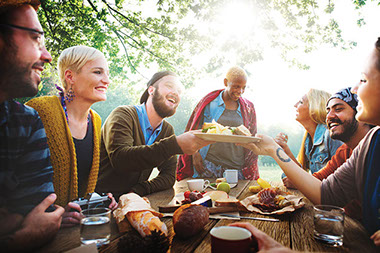 Image of a group of friends eating at a pinic table.