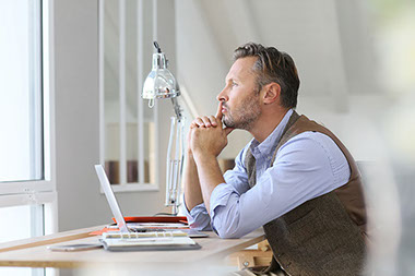 Image of man thinking at desk.