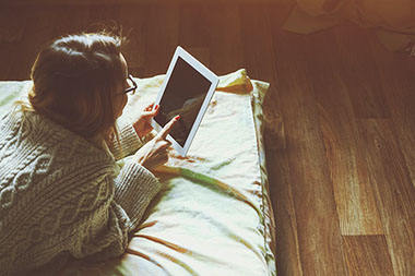 Image of a young female using a tablet in the dark.