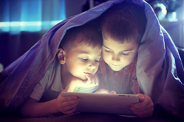 Image of 2 young brothers using a tablet at bedtime.