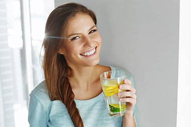Happy woman drinking water with fresh lemon, lime, and mint. Happy woman drinking water with fresh lemon, lime, and mint.