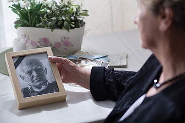 Image of an older women holding a framed picture of husband.