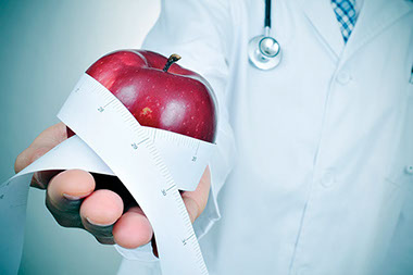 Doctor holding an apple in hand wrap with a tape measure.