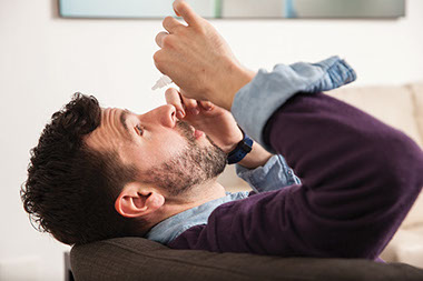 Image of man placing eye drop in eye.