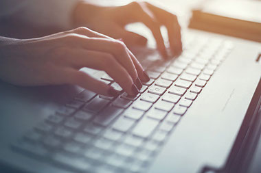 Close up image of hands typing on laptop.