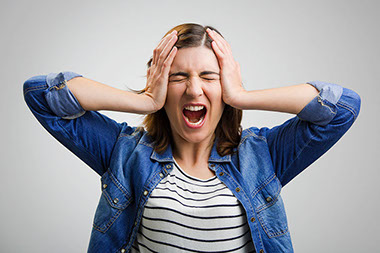 Women with hands on head screaming.