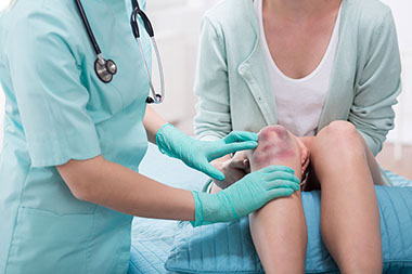 Image of nurse examing patient bruise on knee.