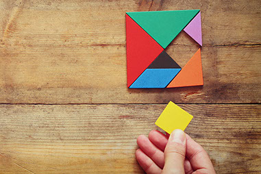 Image of hand holding a missing piece in a square puzzle.