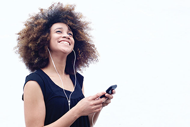 Image of young women smiling while listening to music from her smart phone.