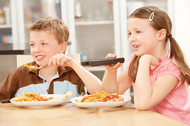 Image of 2 children eating dinner.