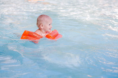 Sun safety tips for infants and babies. Image of toddler swimming.