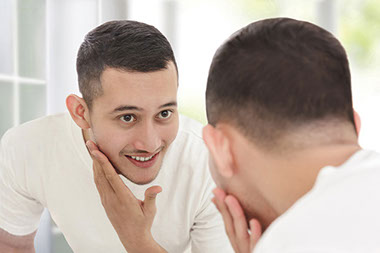 Image of man looking at face in mirror.