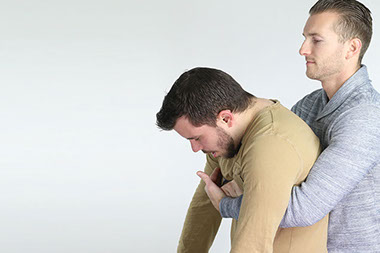 Image of a man performing the Heimlich maneuver.