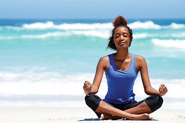 Women mediating on beach.