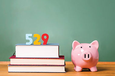 Planning for your childs college expenses Image of piggy bank next to '529' blocks on top of books.