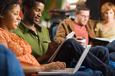 Image of adults writing and using a computer.