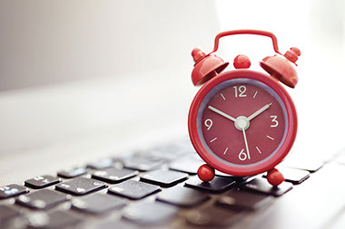 Clock sitting on top of keyboard.