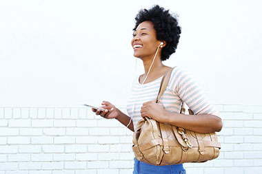 Women holding cell phone with head phones on. Women holding cell phone with head phones on.