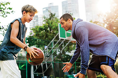 Adult and teen playing basketball.
